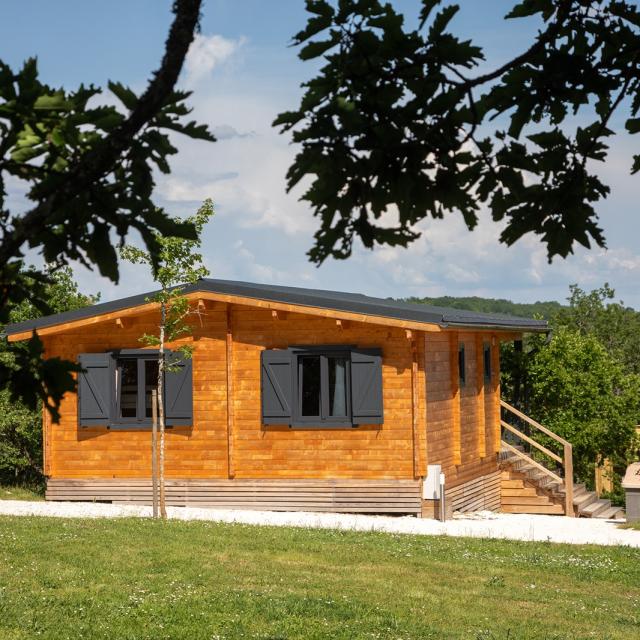 Vue de l'un des 6 chalets en bois de la Truffière dans son cadre nature avec sa terrasse équipée de barbecue,transat...