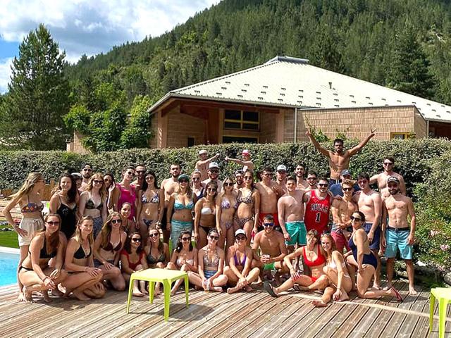 Un grand groupe de touristes qui pose en maillot de bain devant la piscine du village vacances